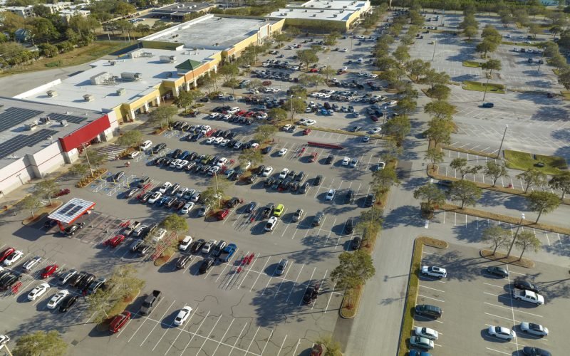 Top view of many cars parked on a parking lot in front of a shopping mall in Florida. Concept of urban transportation.